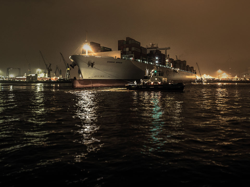 Motiv Containerschiffe bei Nacht mit Schlepper